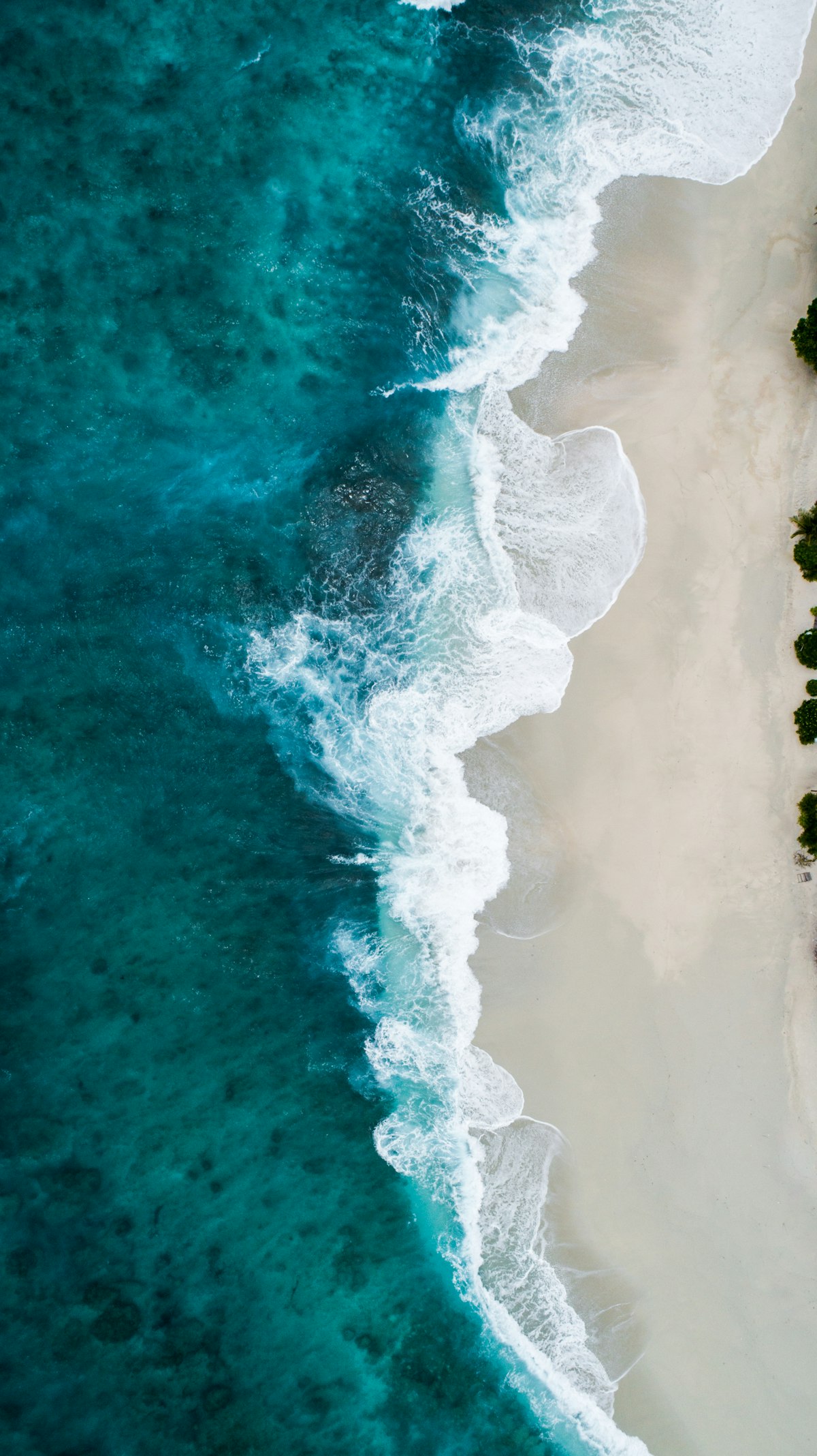 Aerial view of ocean water meeting the sand — placeholder imagery